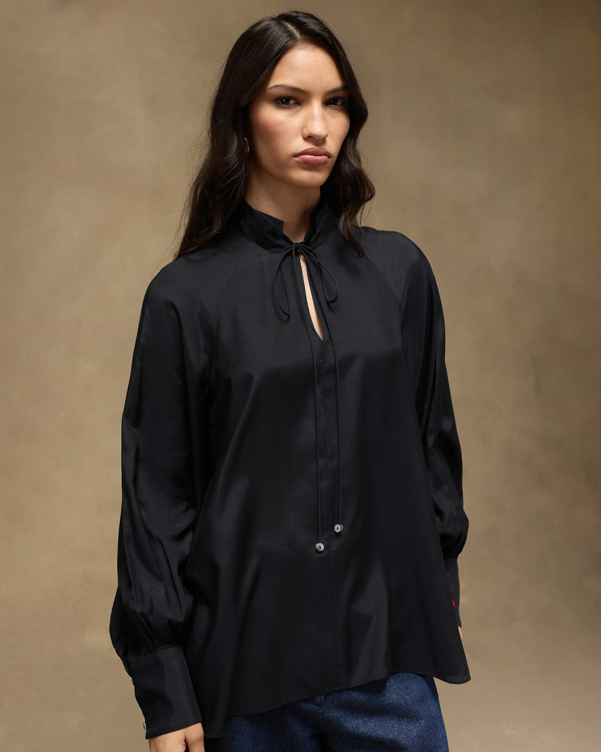 Person wearing a black high-neck top with keyhole ties.