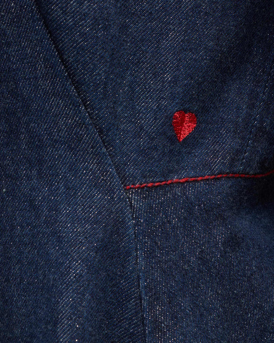 Close-up of a tiny red heart embroidered above the waist seam of the Sway Dress, with red topstitching.