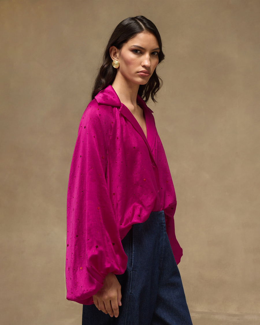 Side view of the fuchsia Cloud Overlay worn loose over dark denim.