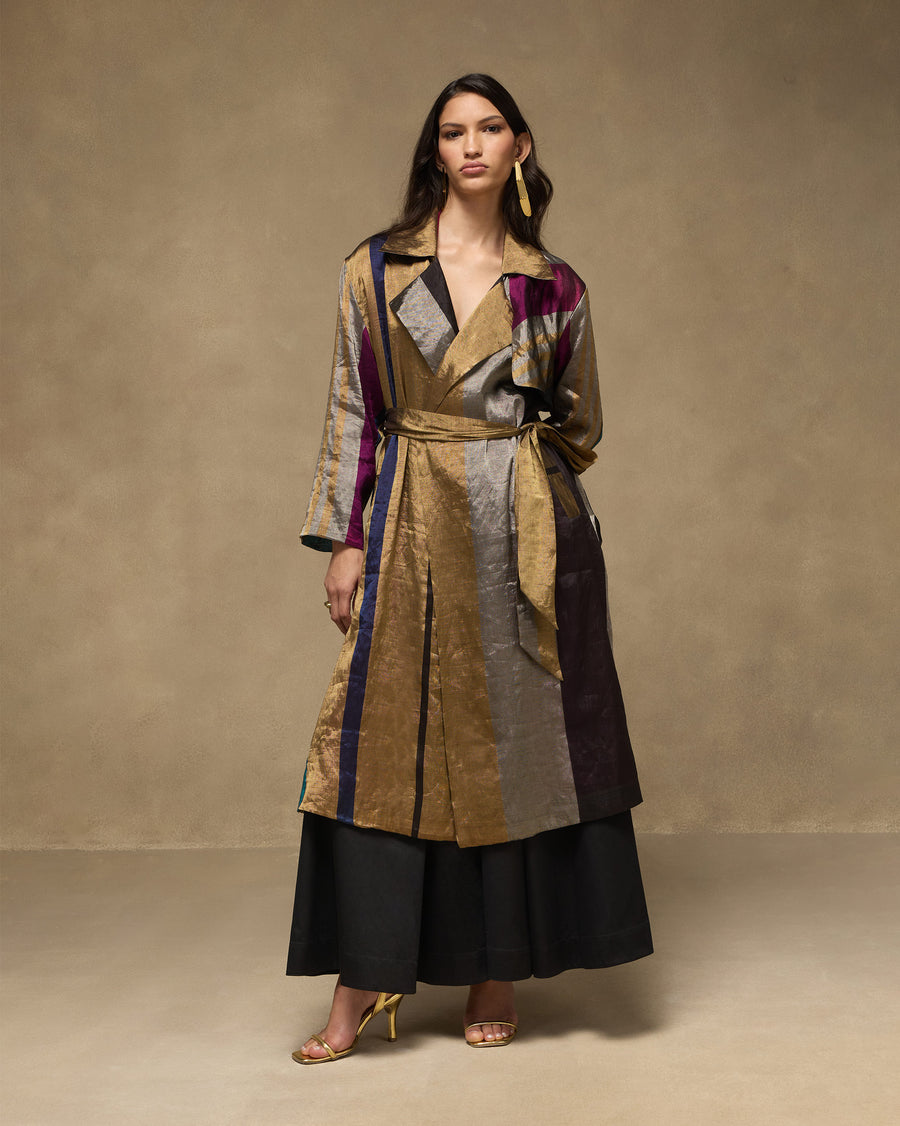The Sera Trench belted at the waist over the black Sway Pants, with gold heels.
