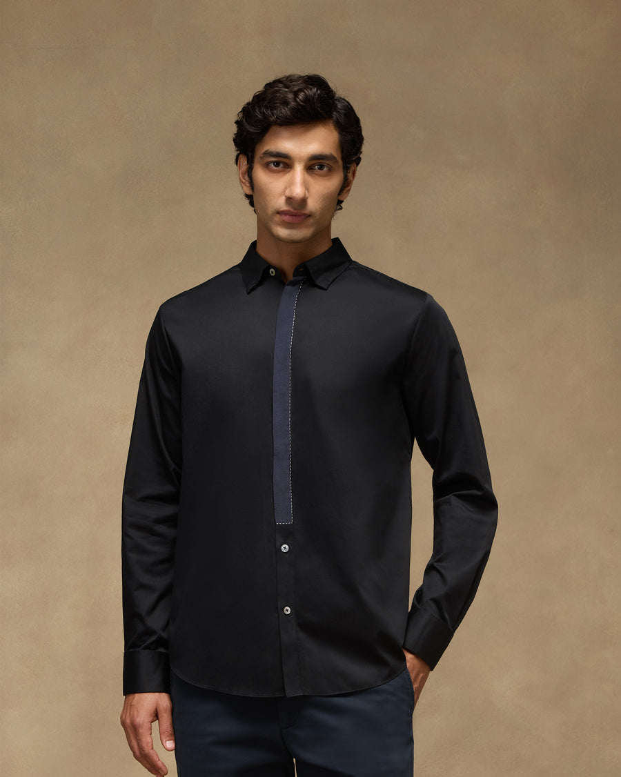 The Midnight Shirt, front view: a black cotton satin shirt with a clean front, worn with navy trousers.