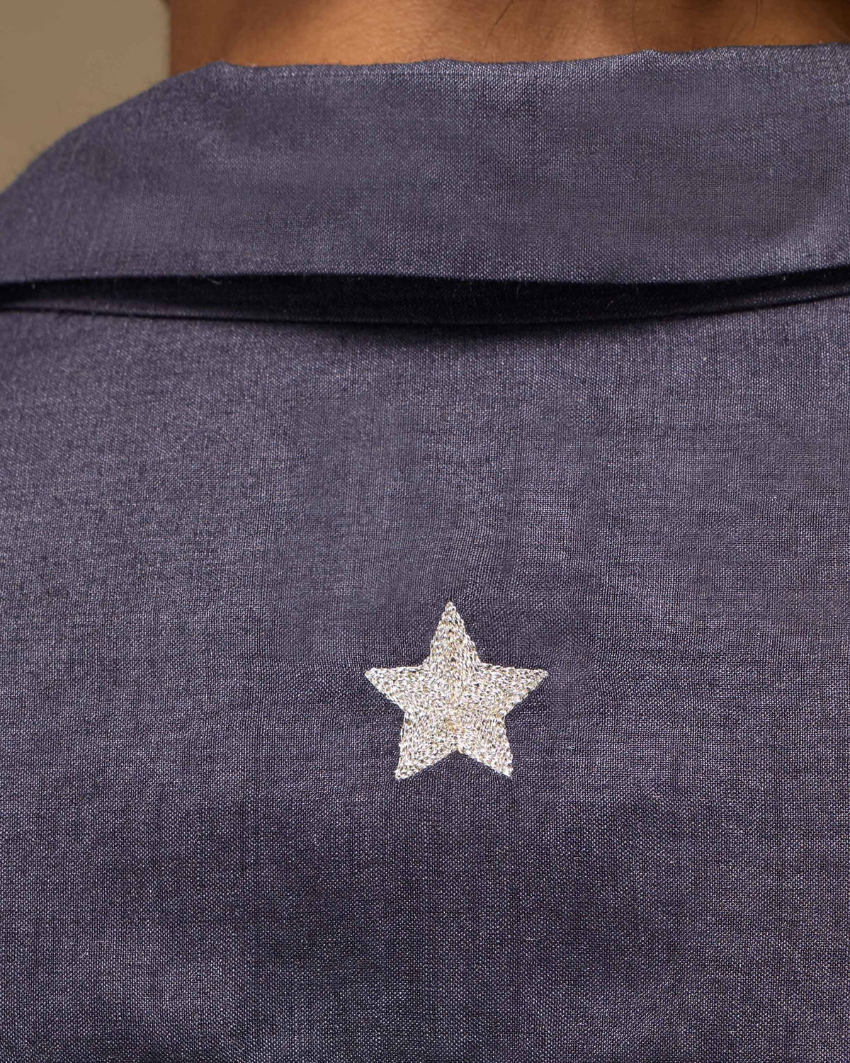 Close-up of a silver star on a light purple Afterglow shirt yoke.