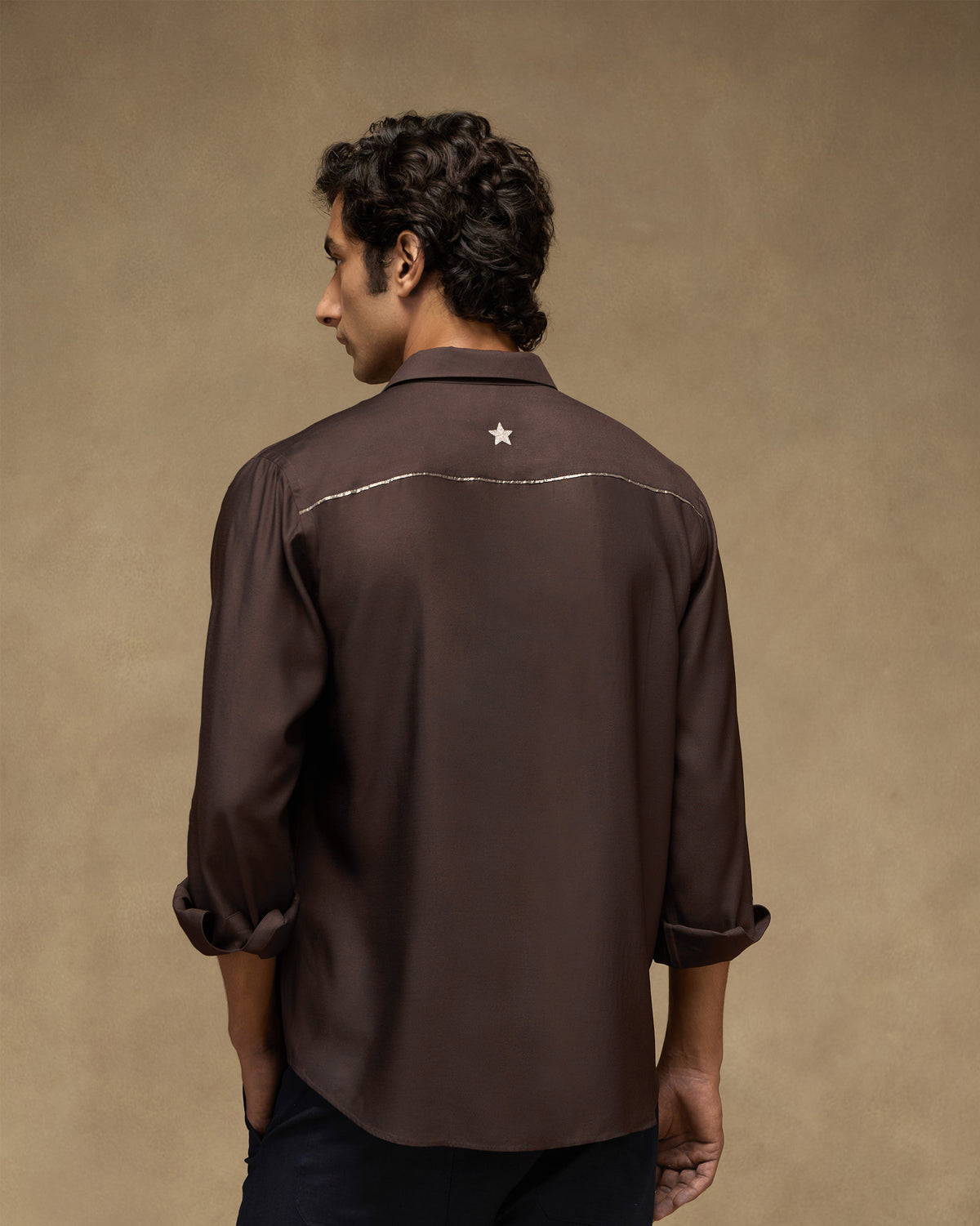 Back of a deep brown Afterhours shirt with a cream embroidered star.