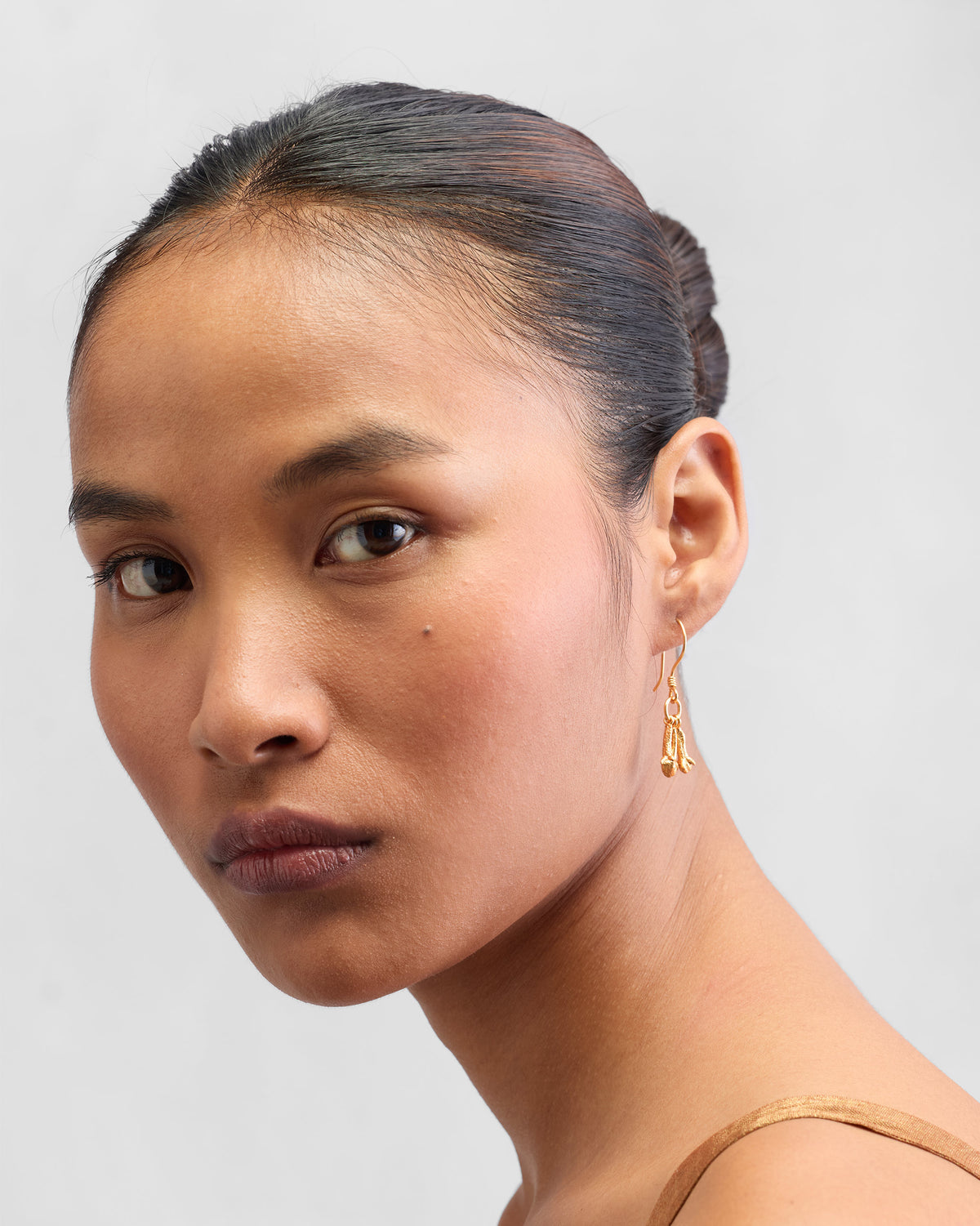 Person wearing Clove Earrings with gold drops below the ear.