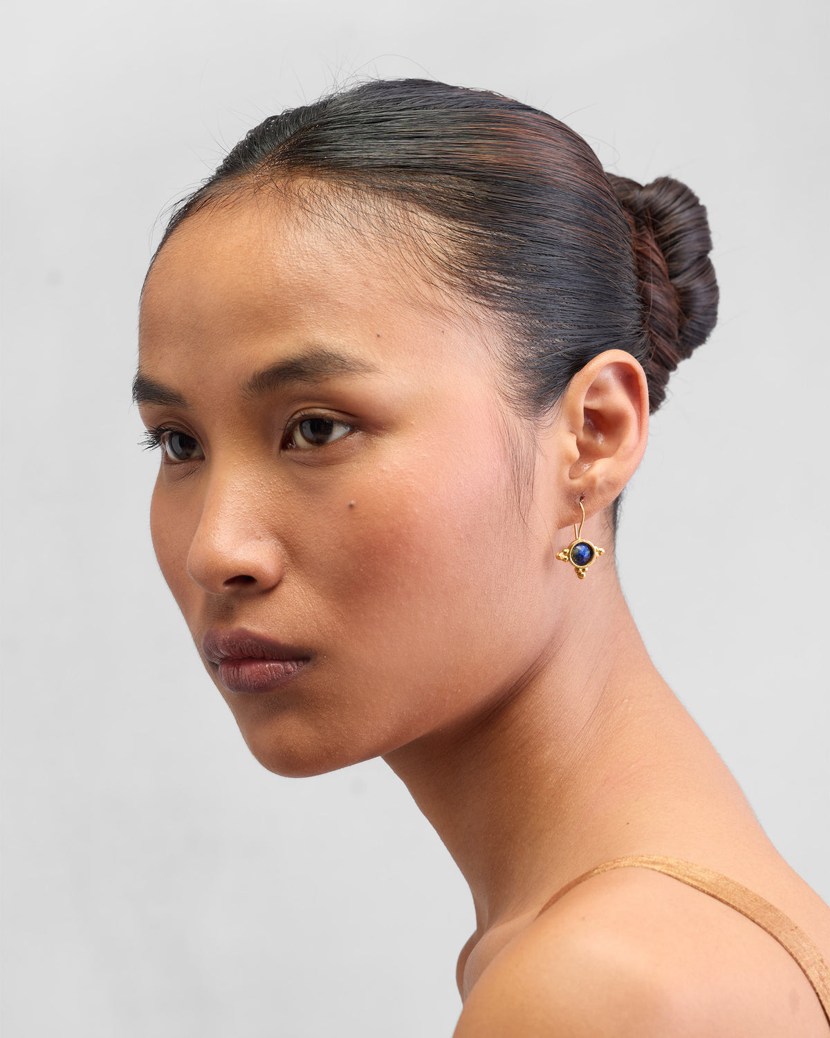 Side view of gold Lapis Drops worn on a person.