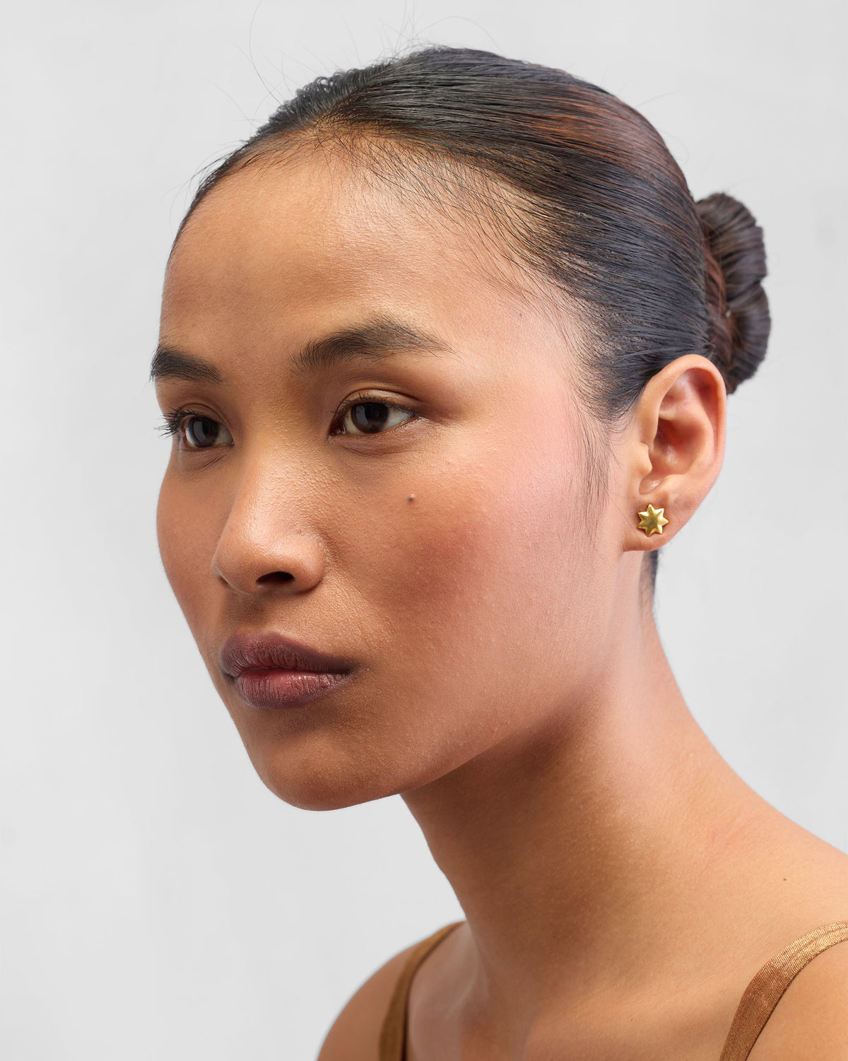 Person wearing gold Sitara Studs, face turned to the side.