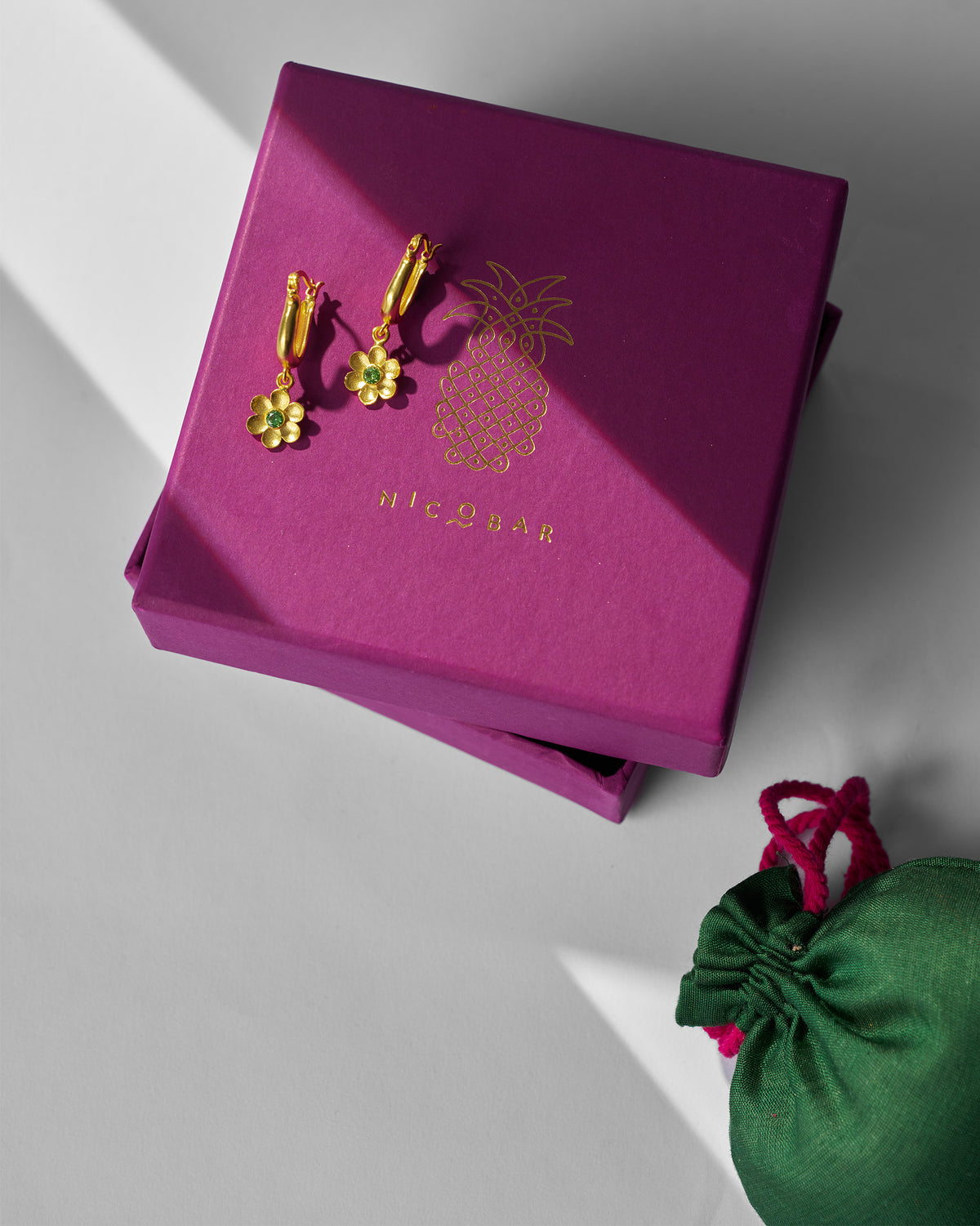 Gold Raat Rani flower earrings on a purple Nicobar gift box.