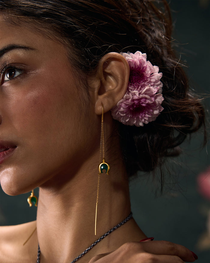 Side profile of gold Chandphool sui dhaga earrings with a green onyx drop on a person.