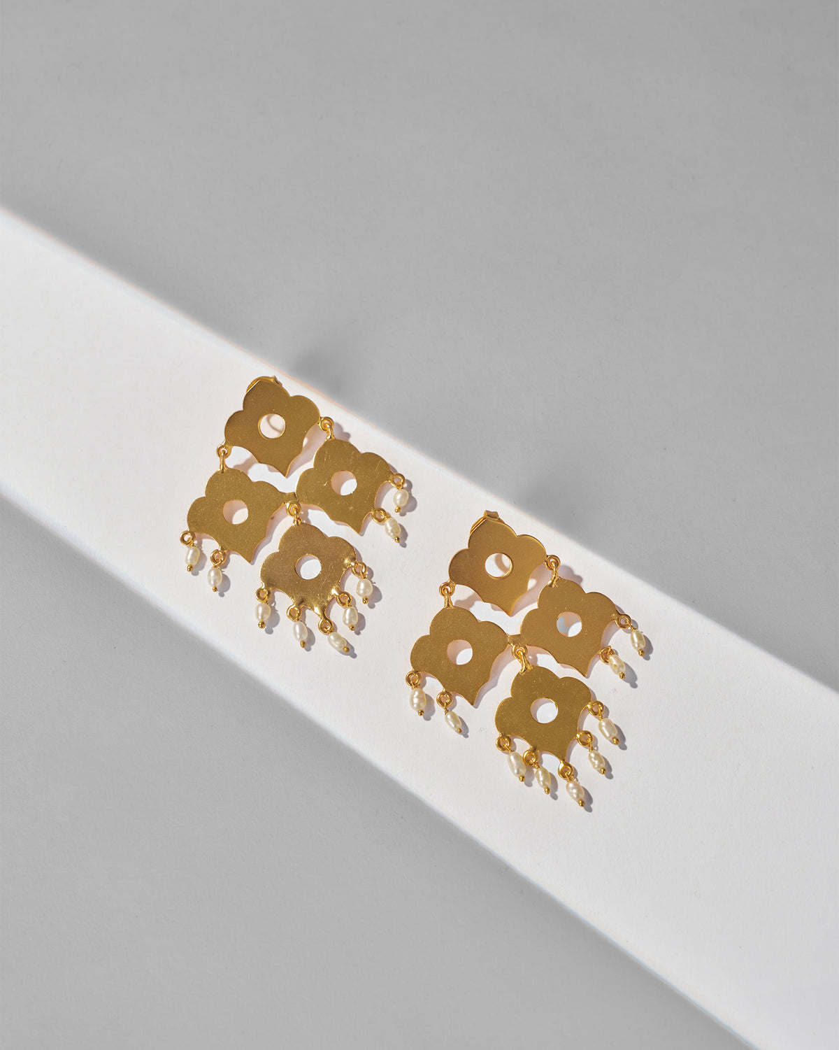 Pair of gold Phool Jaal Earring laid flat, showing pearl drops.