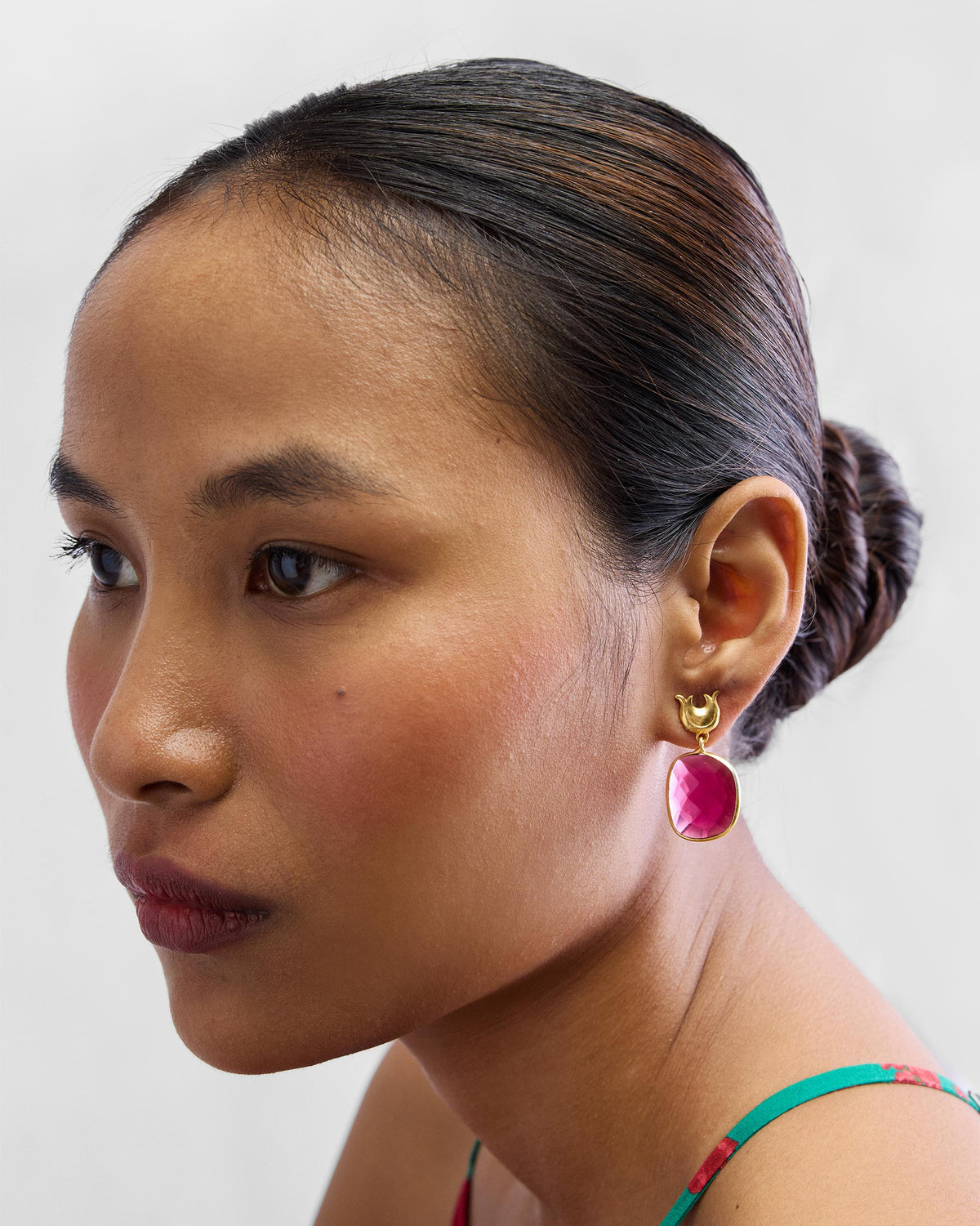 Side view of Chandphool Earrings worn, with a crescent post and pink stone drop.