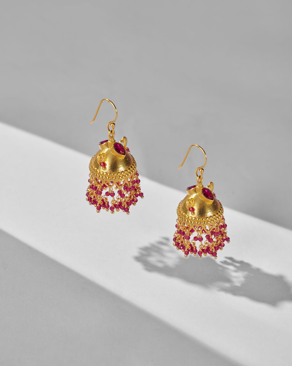 Pair of gold Kaveri jhumkas with red bead fringe.
