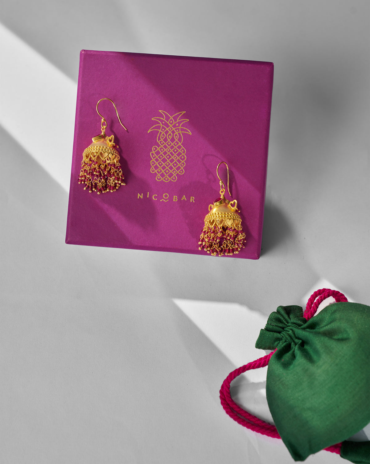 Gold Kaveri jhumkas on a purple Nicobar gift box.