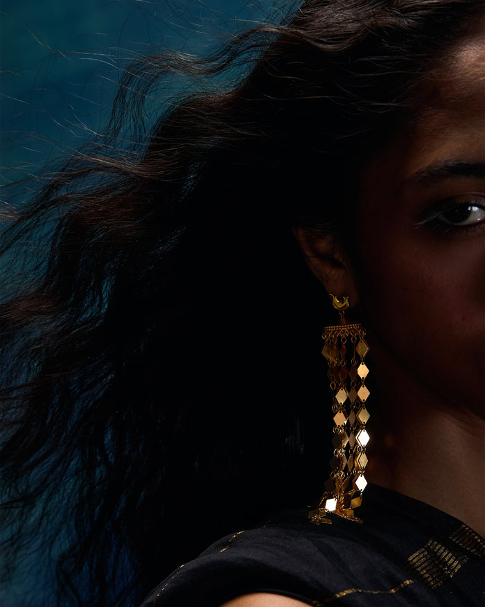 Side profile of long gold Gulbahar earrings with diamond-scale fringe on a person.