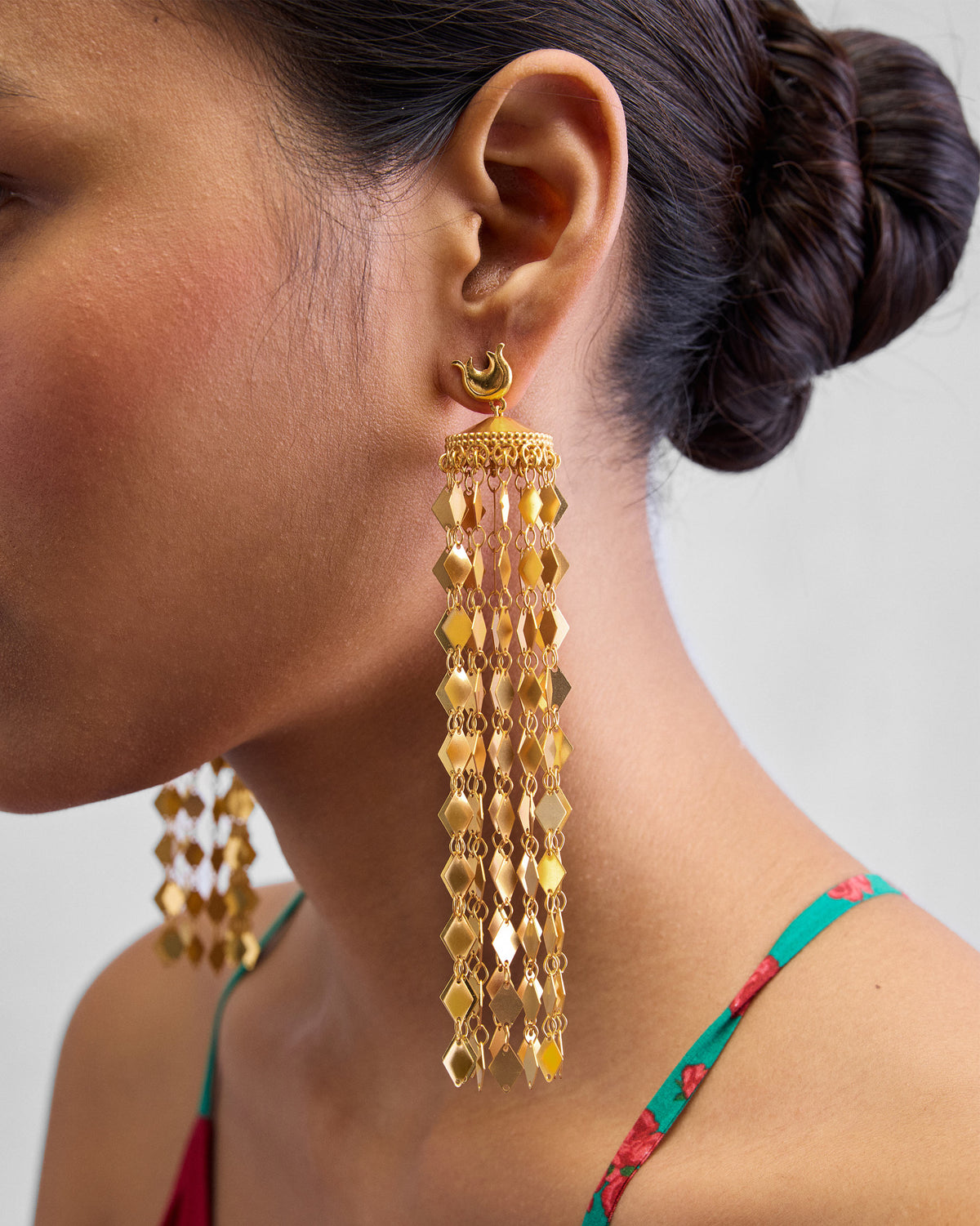Side view of a gold Gulbahar earring with a domed cap and scale fringe.