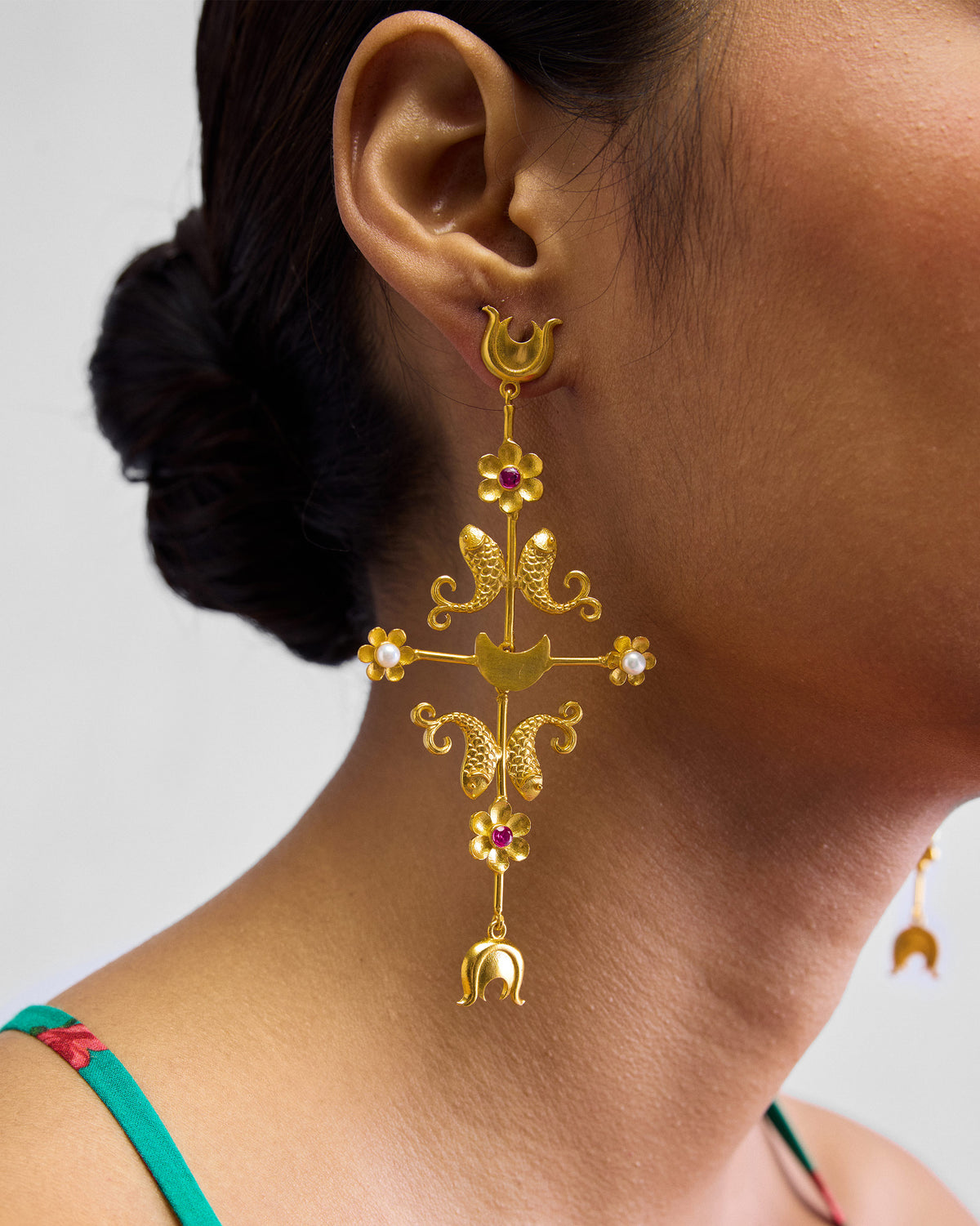 Side profile of a gold gul baag earring with fish and flower motifs.