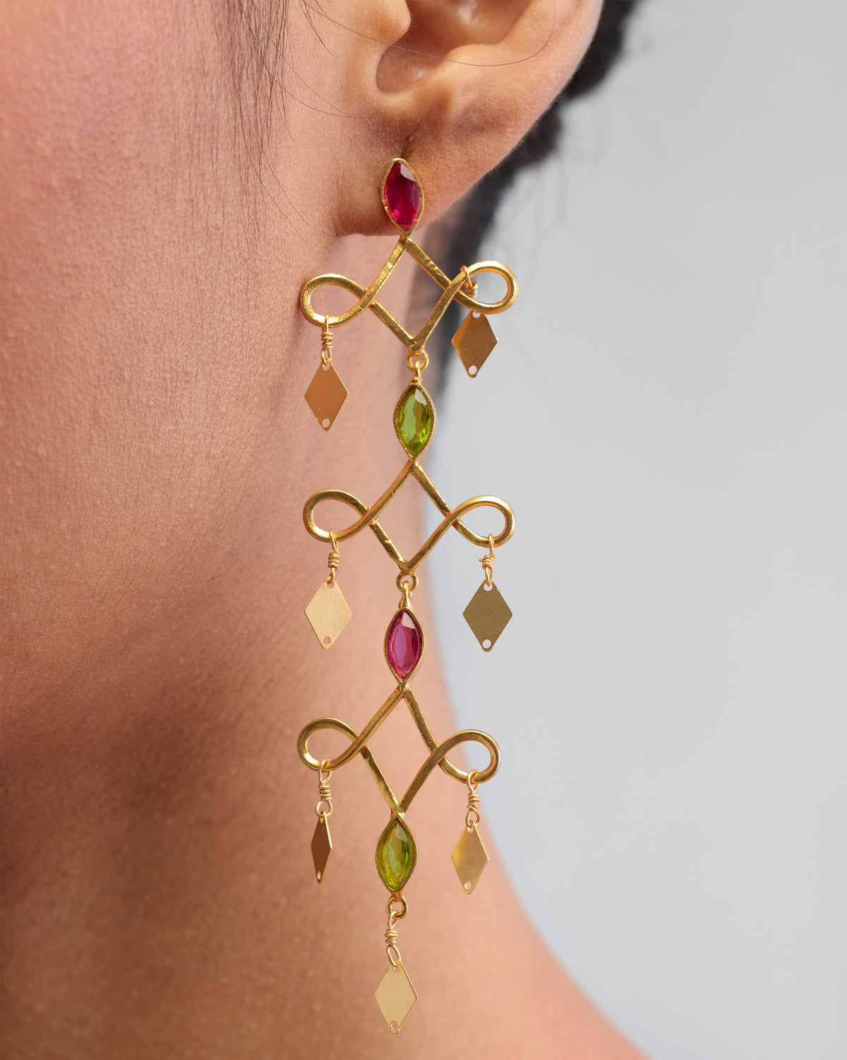 Close-up of Kolam Danglers worn on an ear, showing pink and green stones.