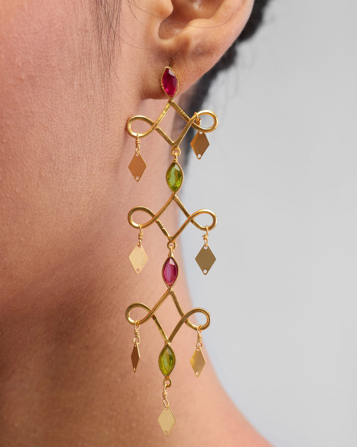 Close-up of Kolam Danglers worn on an ear, showing pink and green stones.