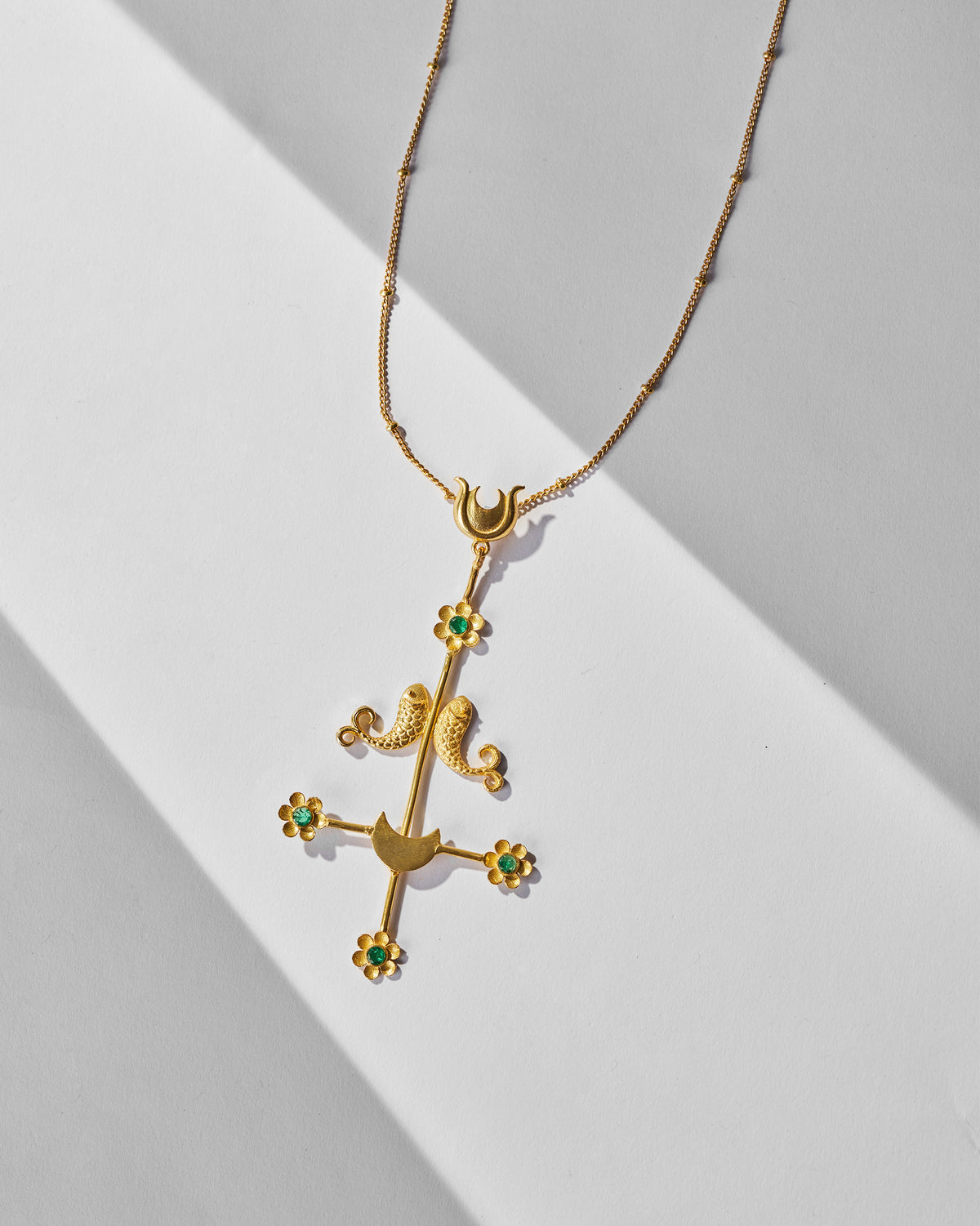 Gold Gul Baag pendant showing facing fish, crescents and green flower stones.