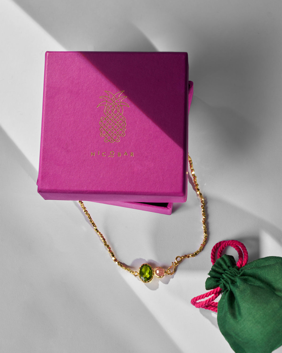 Gold Kari necklace beside a pink Nicobar jewellery box and pouch.