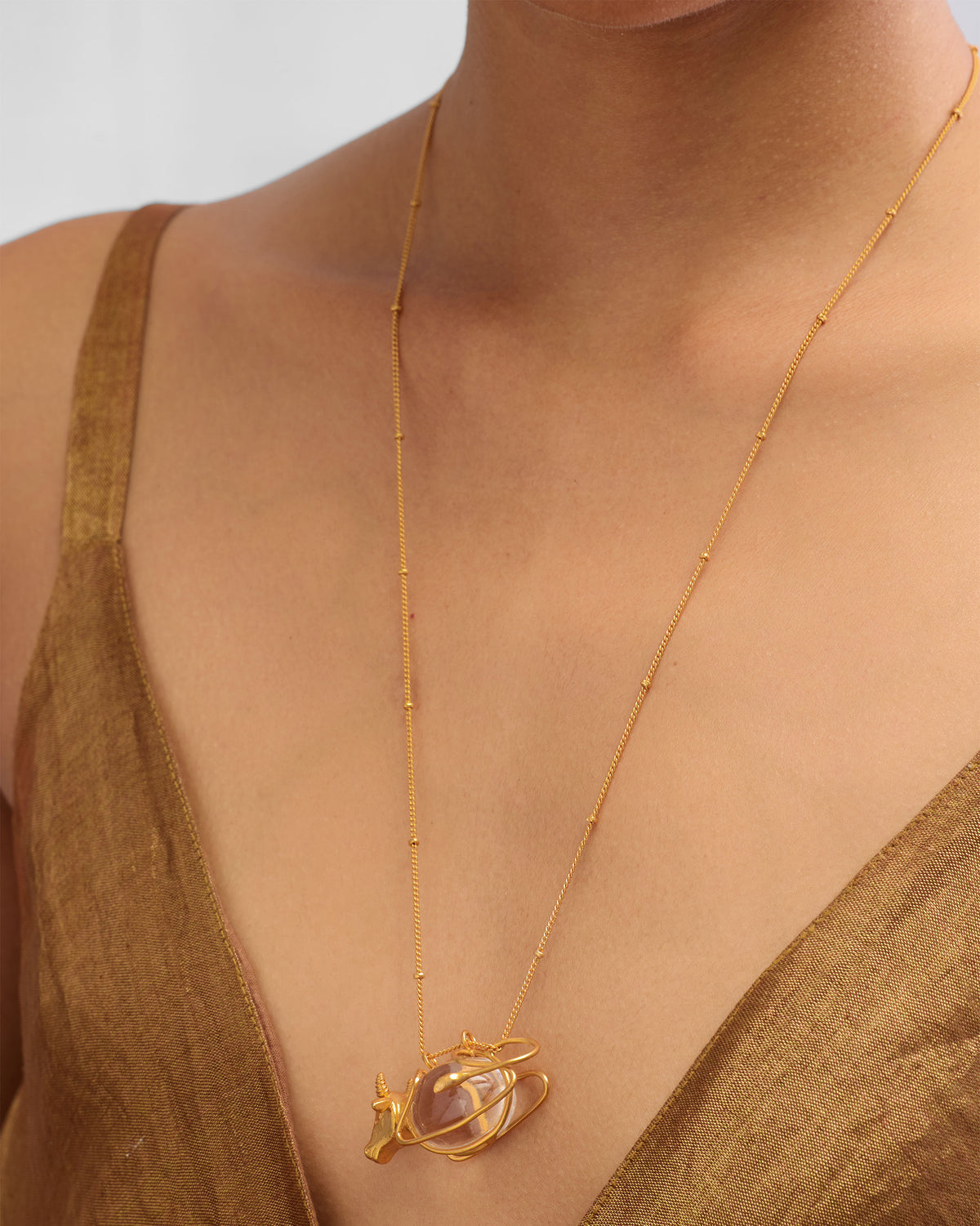 Person wearing a gold Nandi necklace with a bull pendant and clear orb.