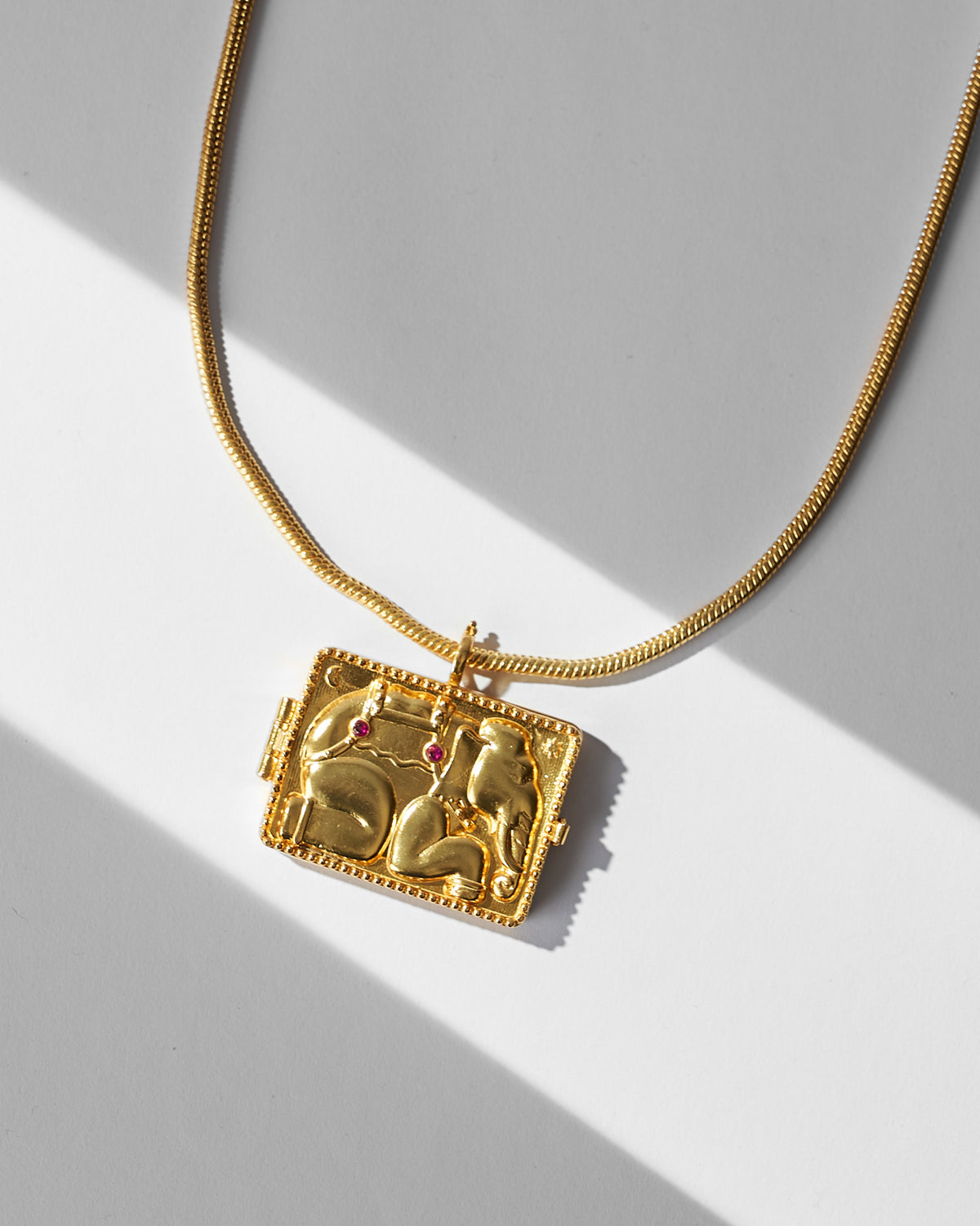 Close-up of the gold Appu elephant locket pendant with red stone eyes.