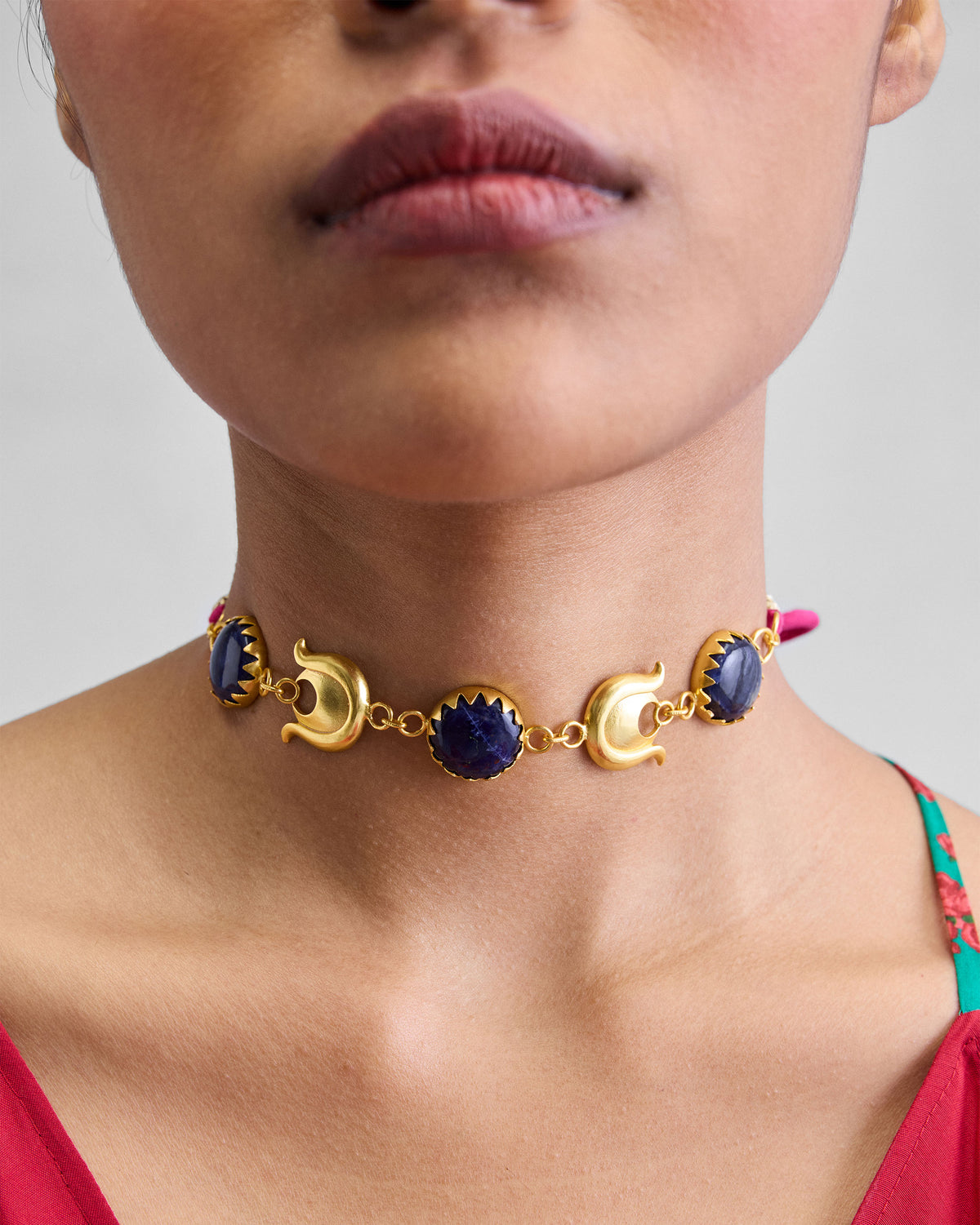 Close-up of a Chandphool Choker with gold crescents and blue stones worn at the neck.