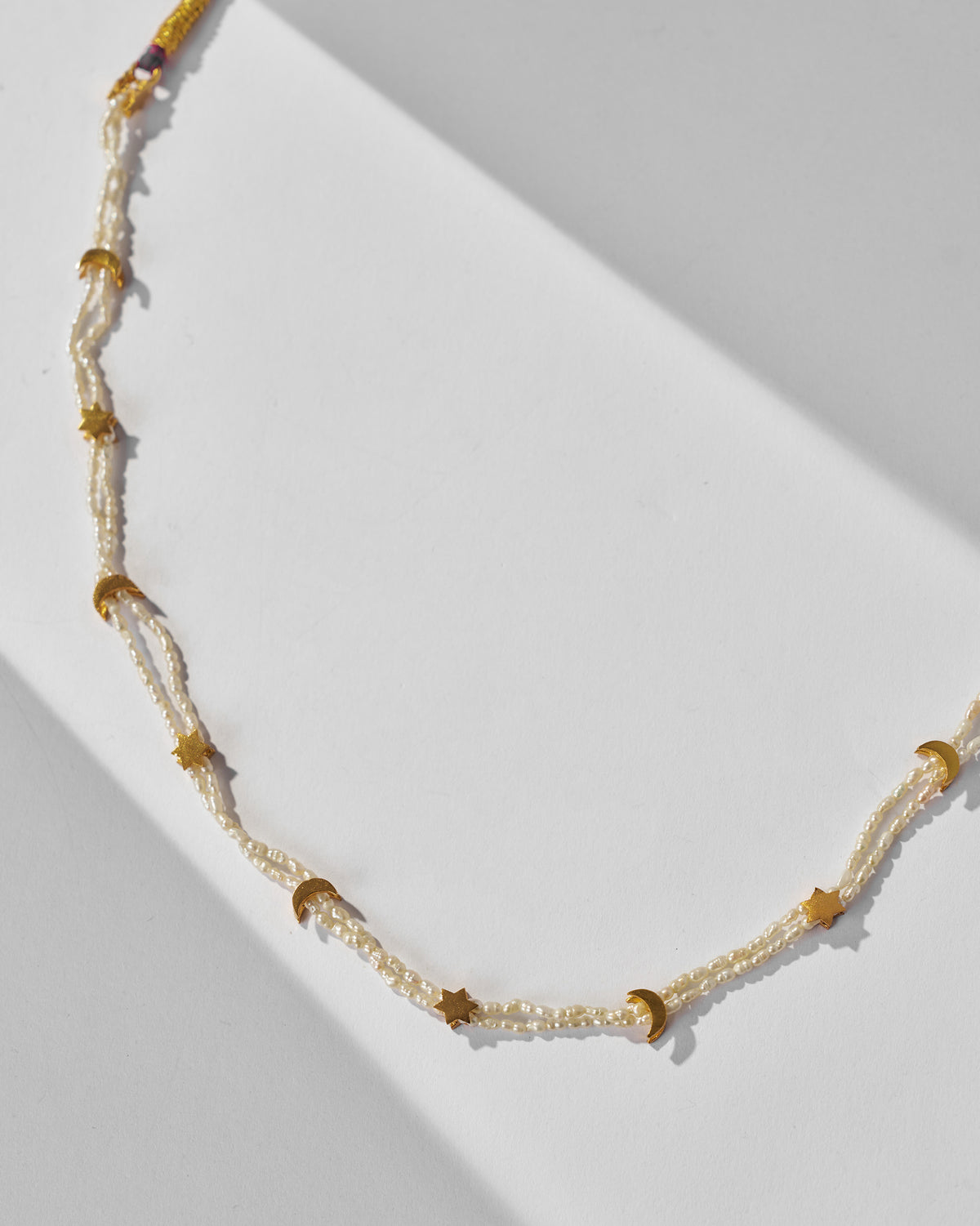 Close-up of Bindu pearl strands with gold moon and star charms.