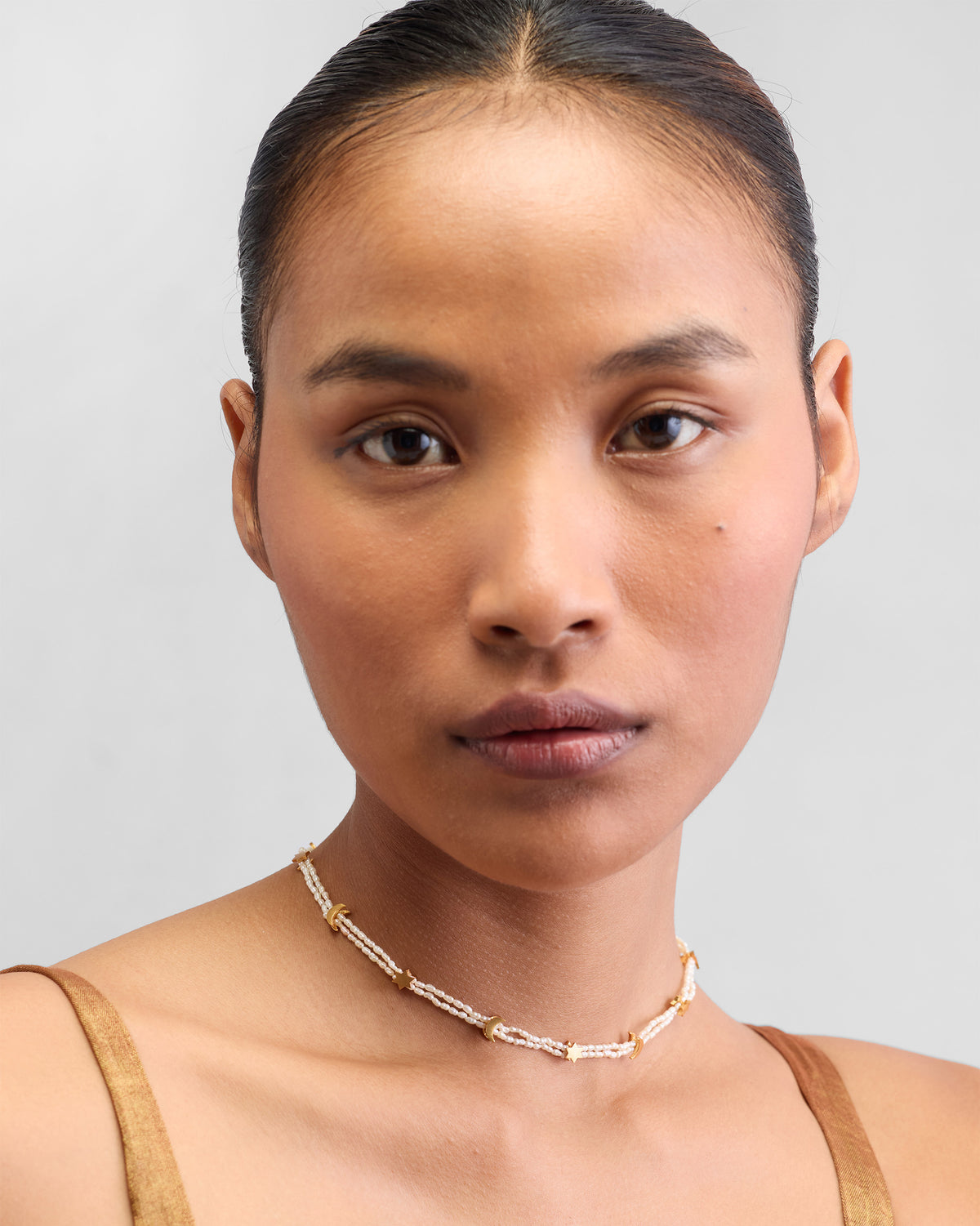 Person wearing a gold Bindu pearl necklace with star charms.