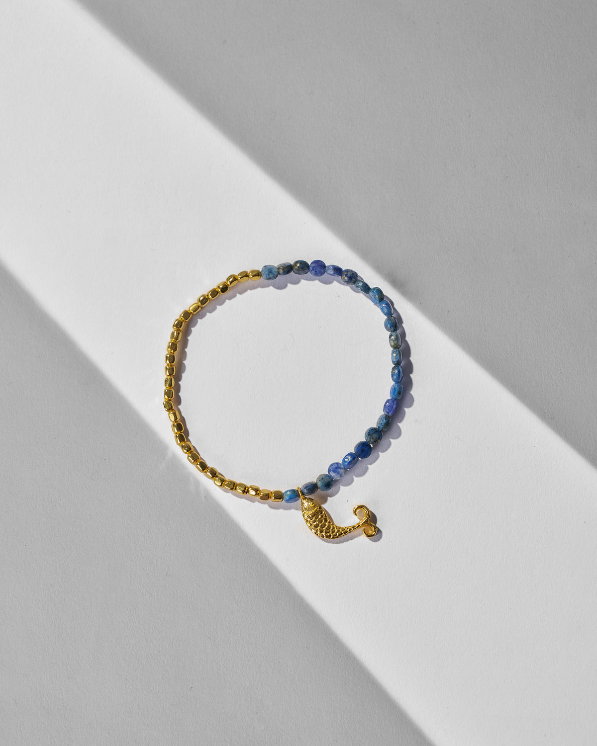 Jalpari Bracelet with gold and blue beads laid flat on a white surface.