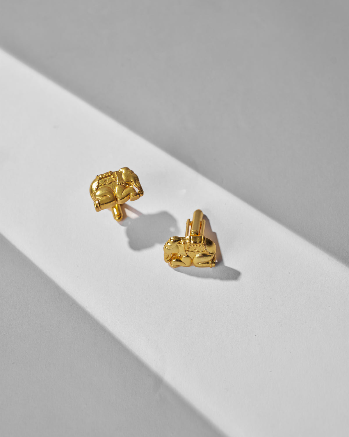 Pair of Appu Cufflinks angled on white, showing their gold posts and elephant motif.