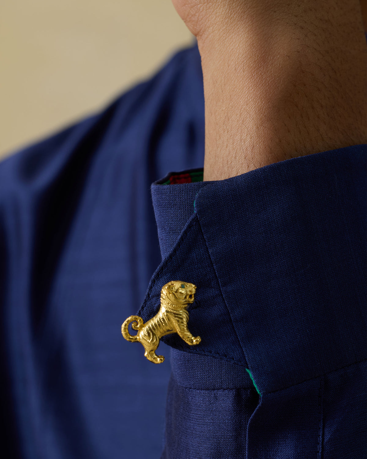 Close-up of a Roar Cufflink with a gold tiger motif on a navy shirt cuff.