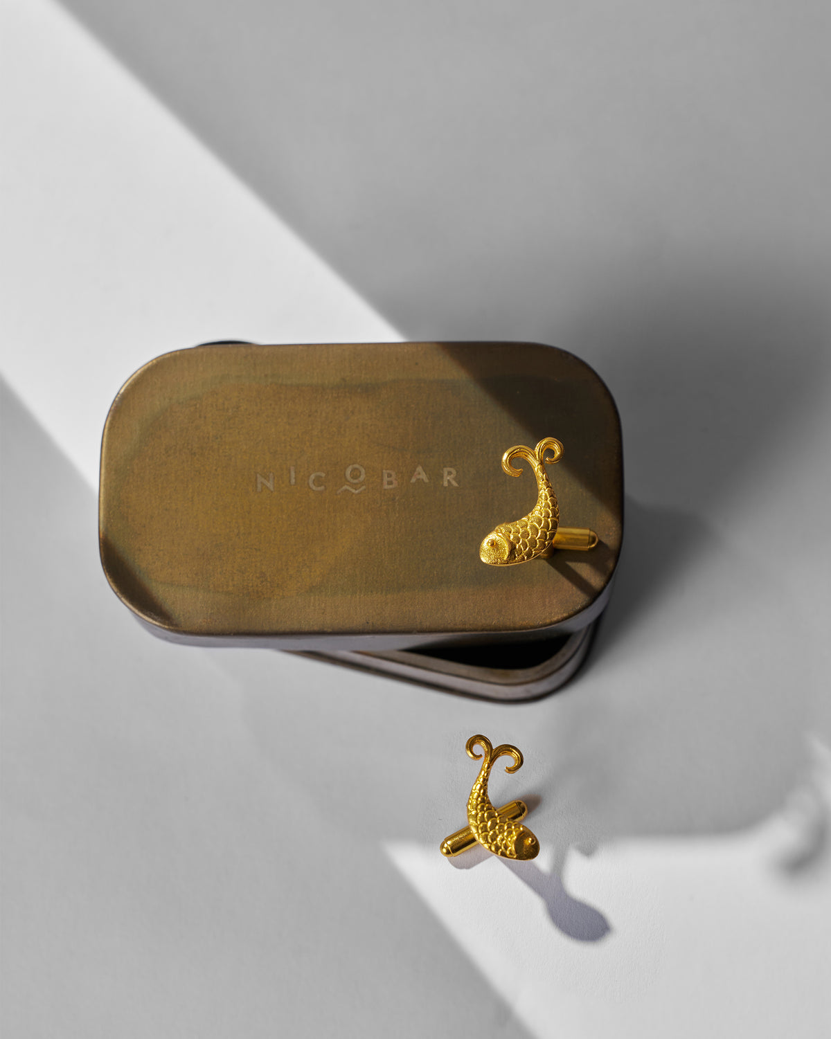 Gold Jalpari Cufflinks resting on a Nicobar tin.