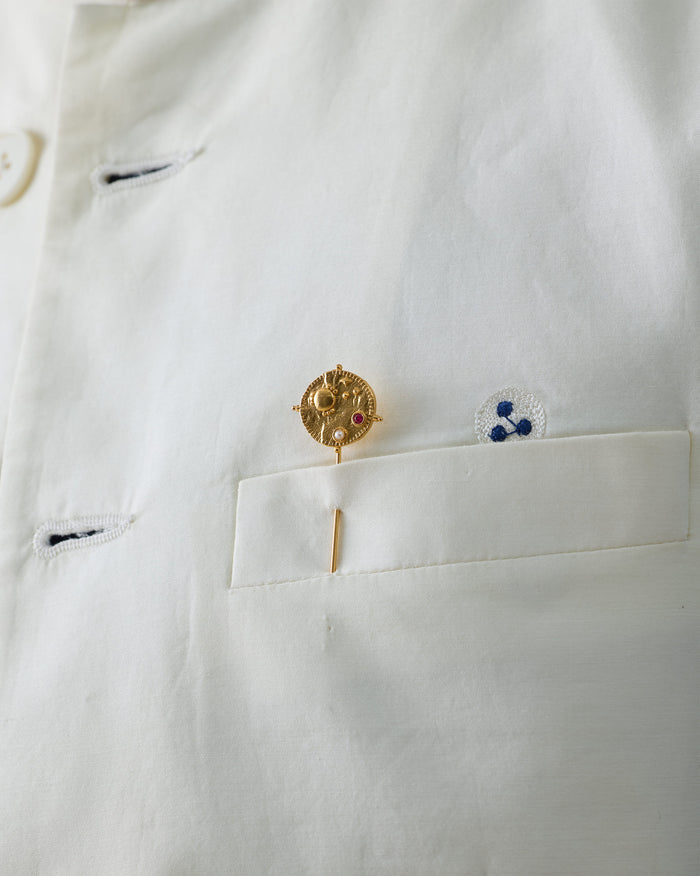 Gold Nebra Lapel Pin with a red stone pinned to a white shirt.