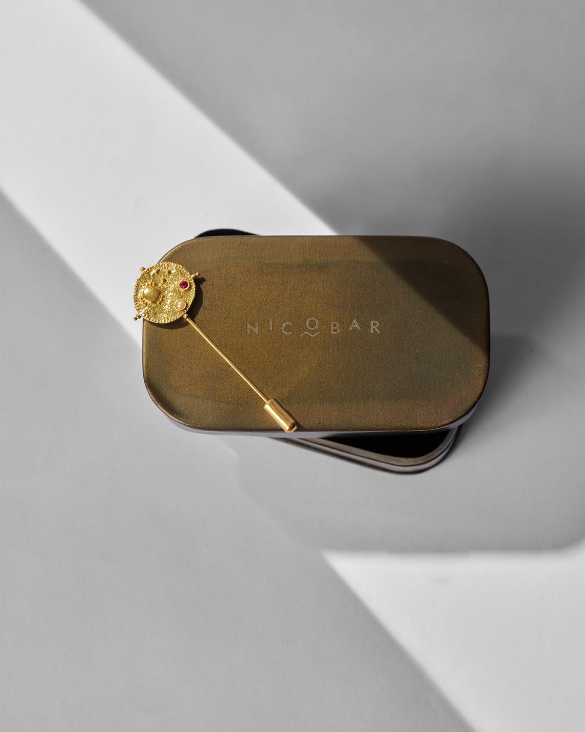 Nebra Lapel Pin resting on a Nicobar tin.