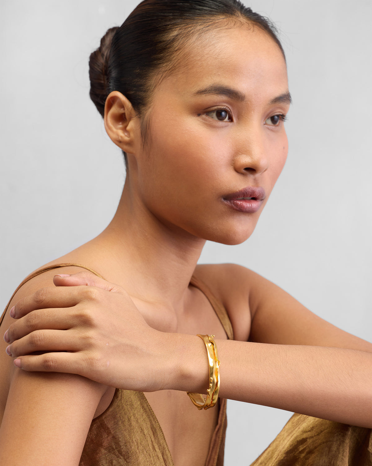 Person wearing a gold Dhaara cuff on the wrist.