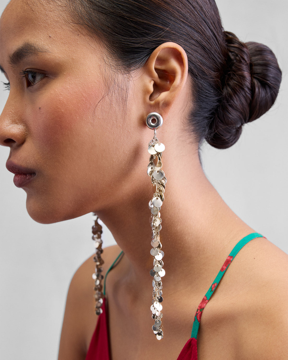 Side profile of long silver tassel shoulder duster earrings.