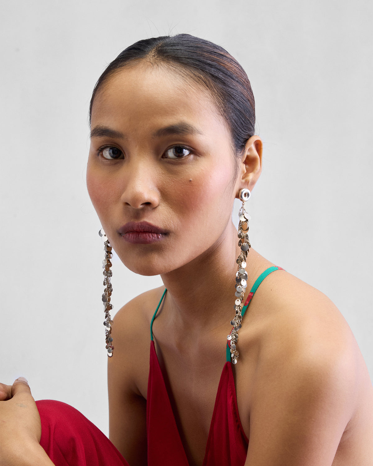 Person wearing long silver tassel shoulder duster earrings with disc fringe.