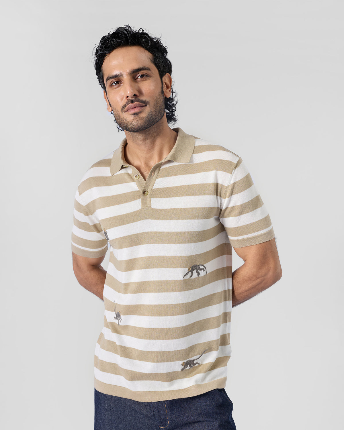 Person wearing an ivory and sand striped Macaque Polo with a classic collar.