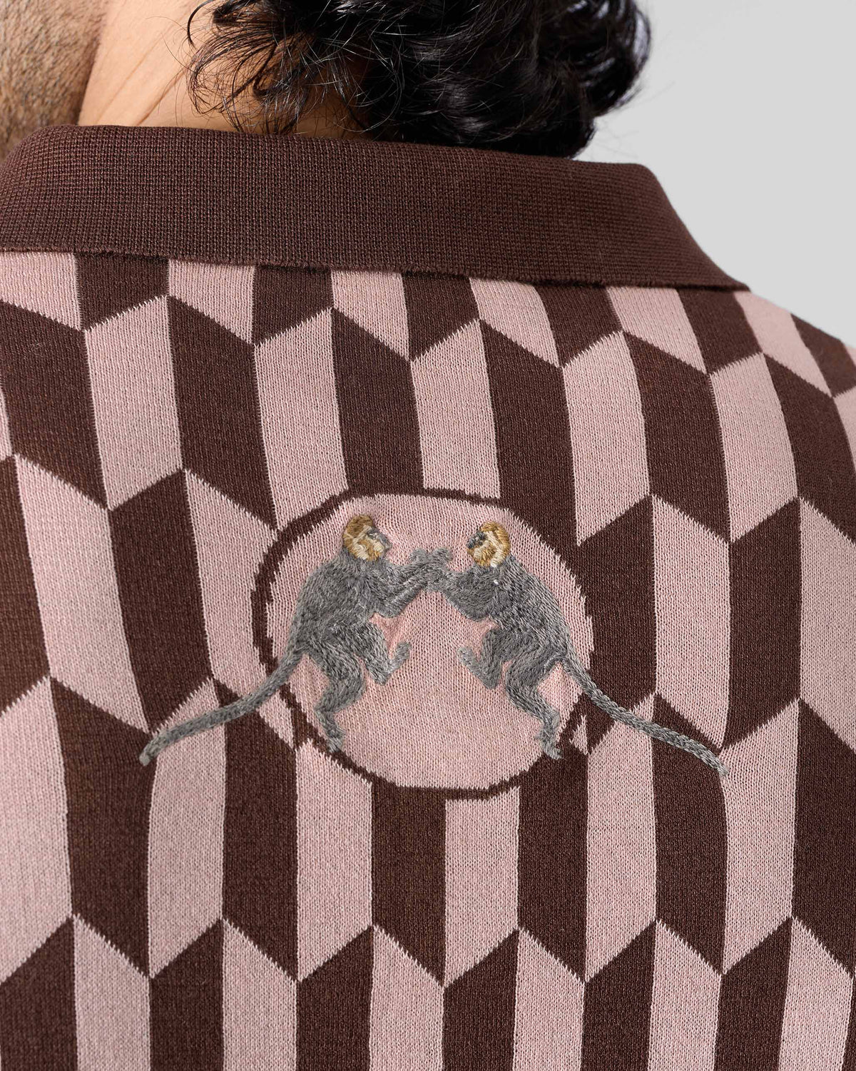 Close-up of paired langur embroidery on the back of a brown-and-pink Langur polo.