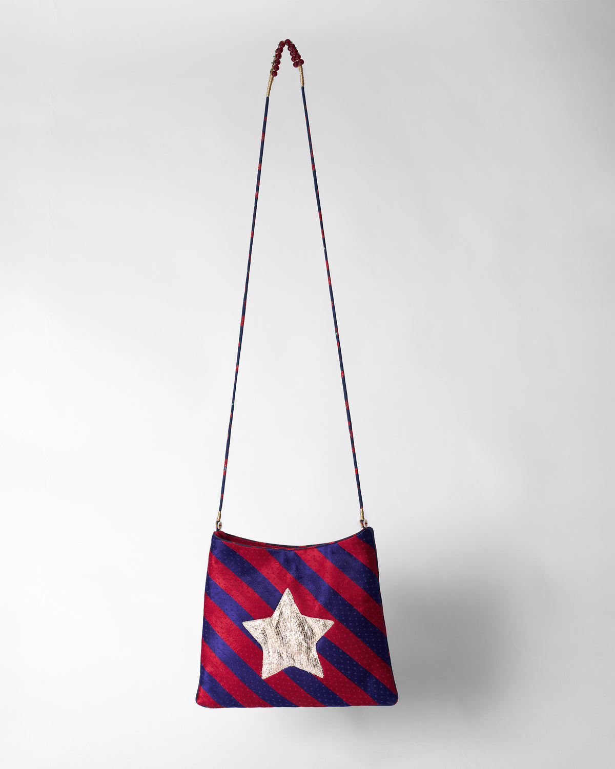 Red and purple Muris Sling with a silver star and beaded strap.