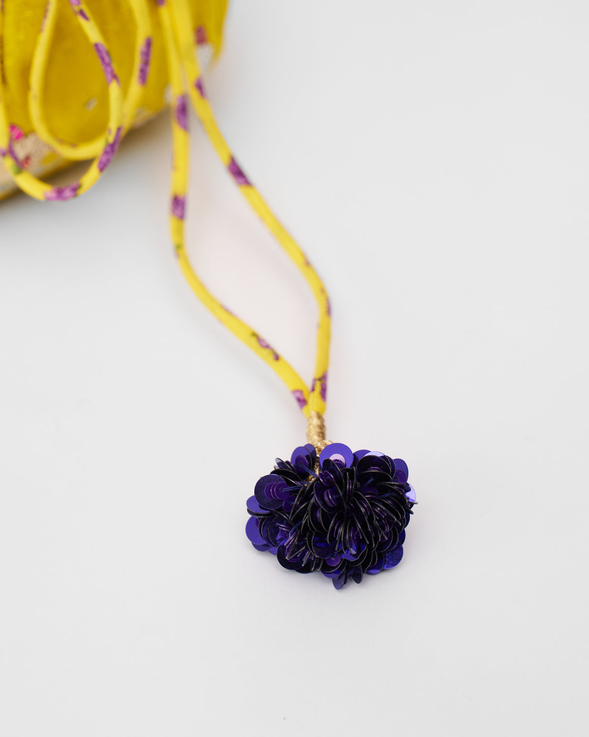 Close-up of a navy sequin tassel on the Firefly Potli's yellow drawstring.