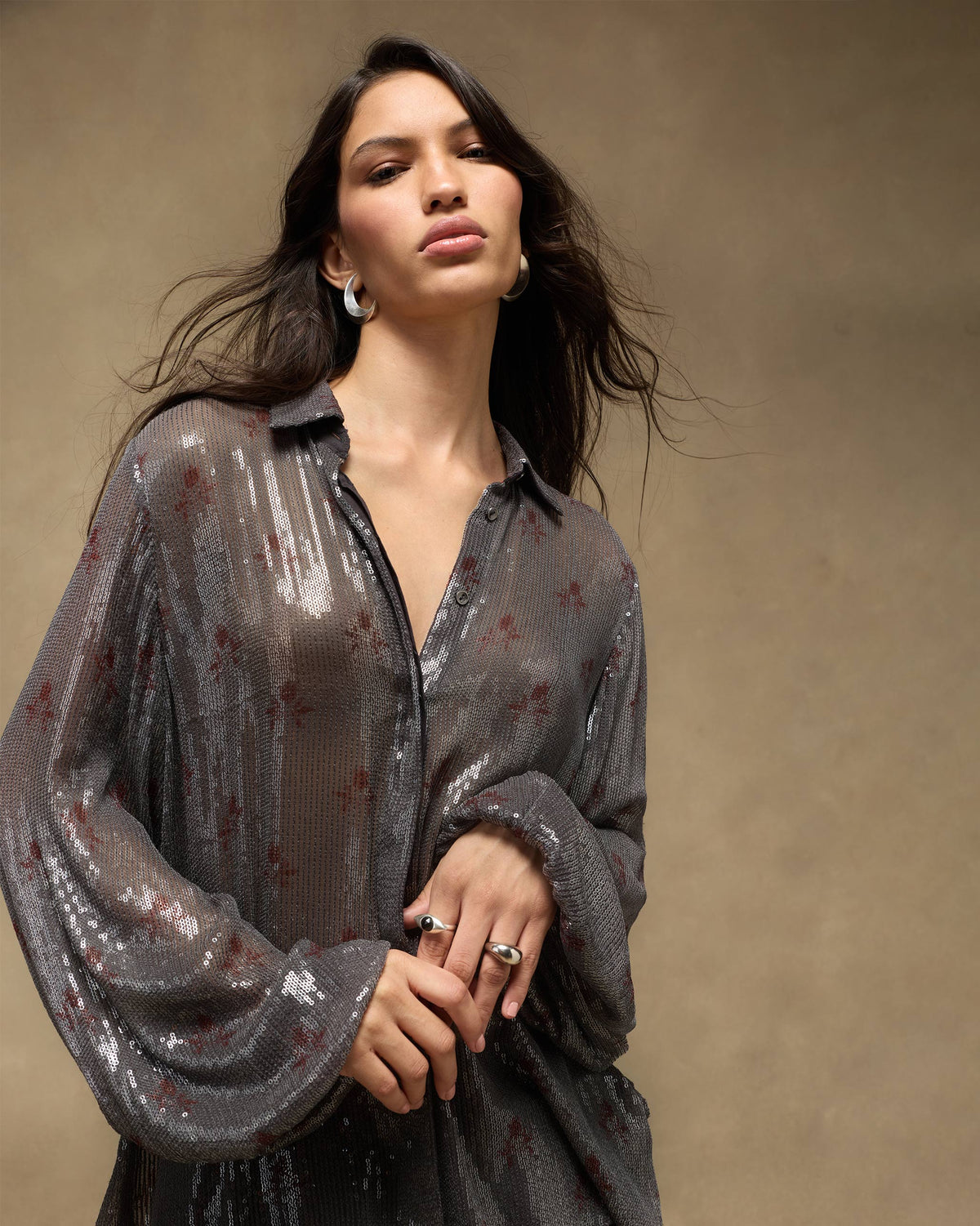 Person wearing a charcoal Bacchus shirt with silver sequins and red tulip motifs.