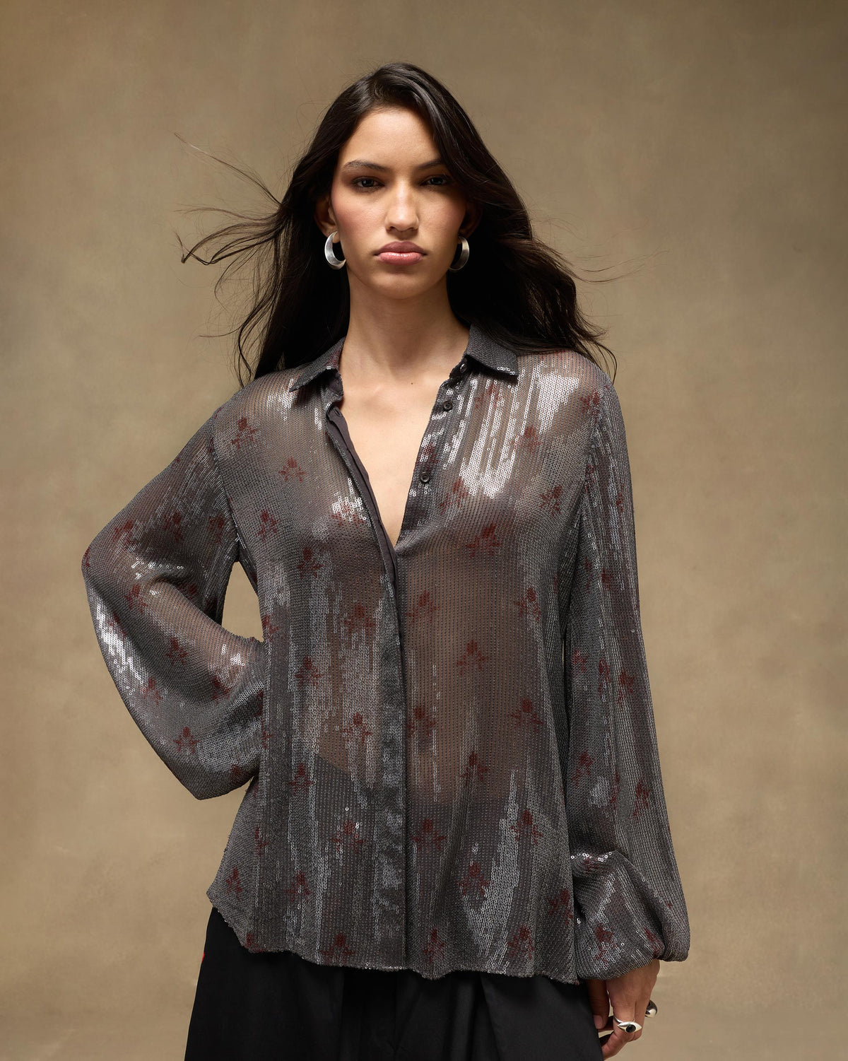 Person wearing an open charcoal Bacchus shirt with silver sequins and red motifs.