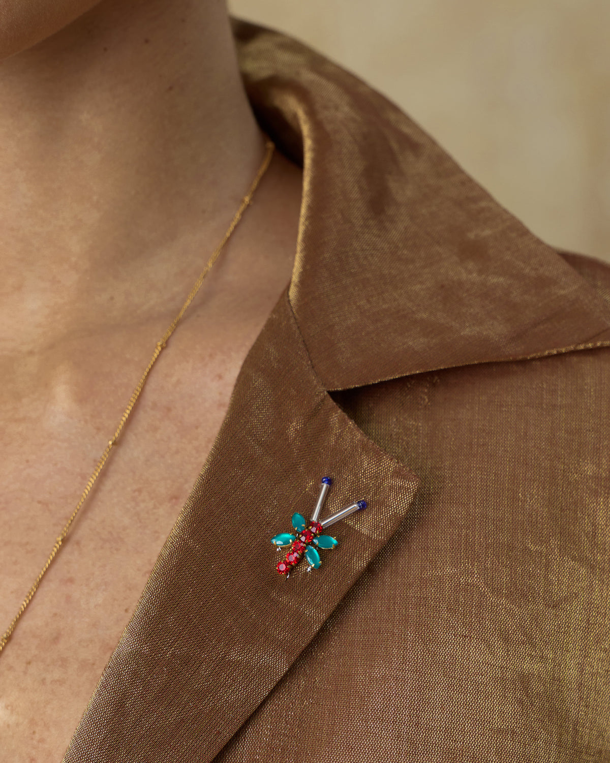 Close-up of a jeweled brooch on a metallic gold shirt lapel.