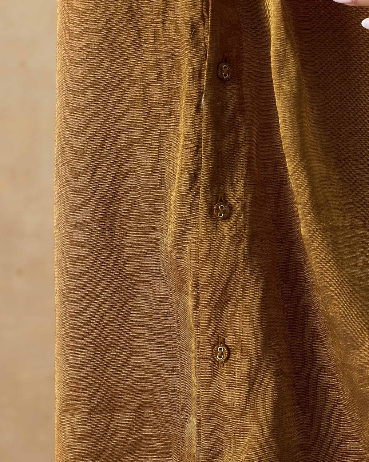 Close-up of buttons on a metallic gold shirt placket.