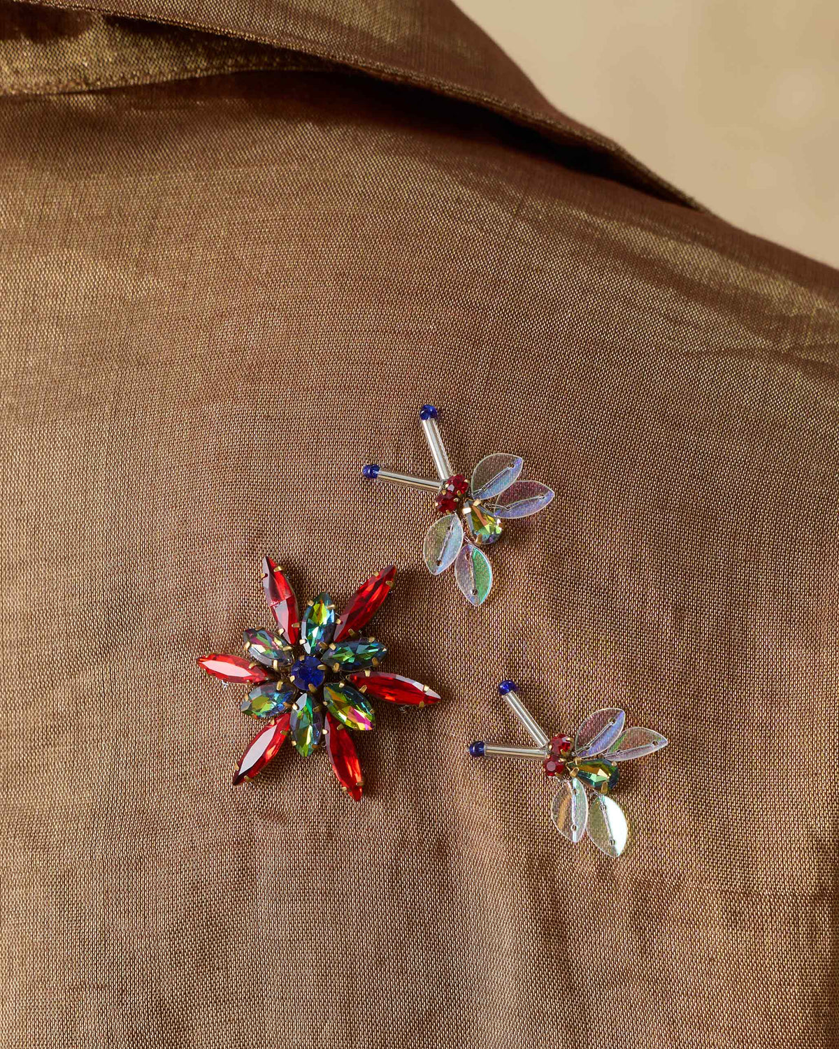 Close-up of jeweled brooches pinned to a metallic gold shirt.