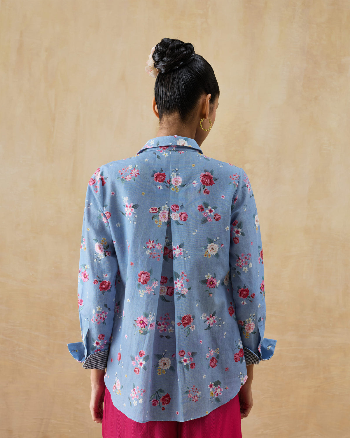Back of an ice blue Detour shirt with a center box pleat and floral print.