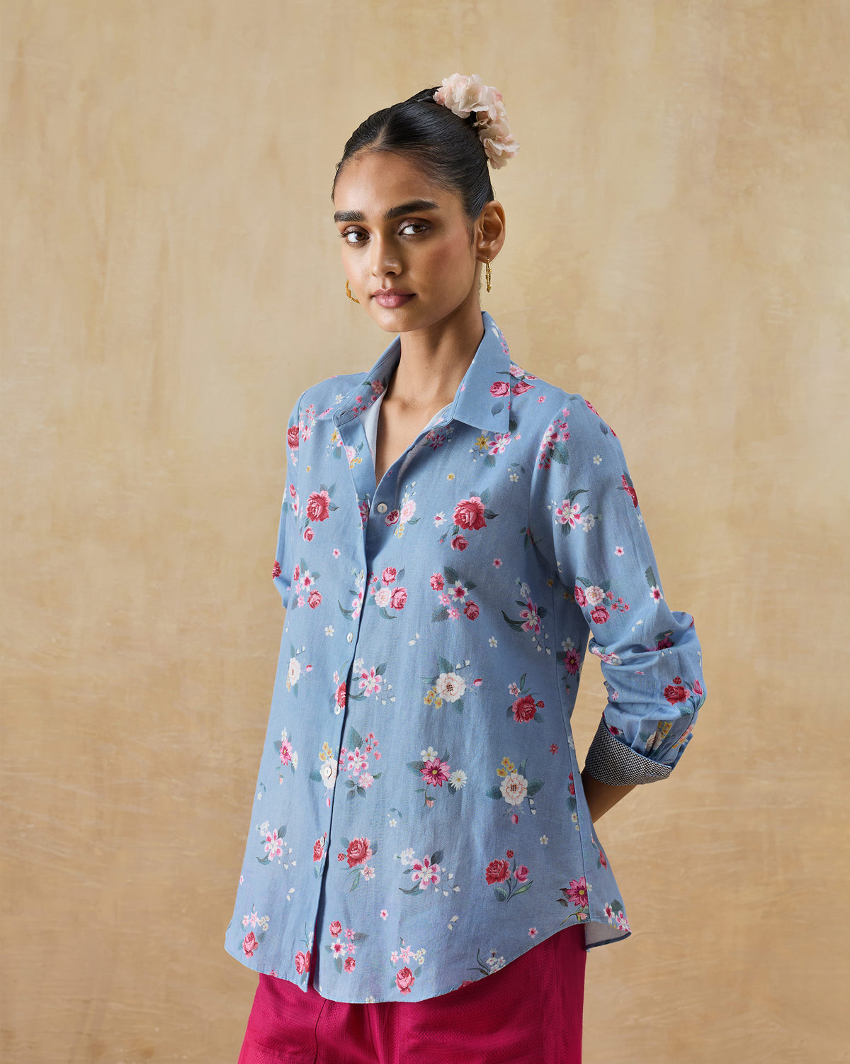 Person wearing an ice blue Detour shirt with rolled sleeves and floral print.