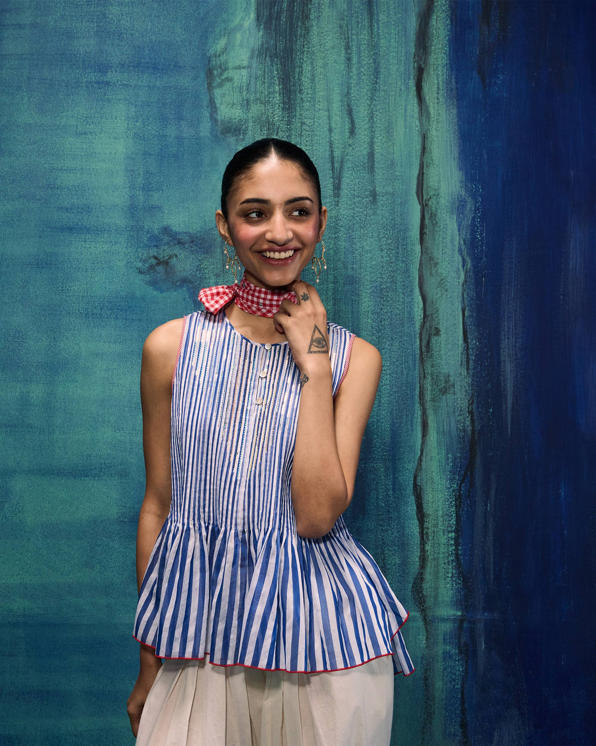 Person wearing a cobalt and ivory striped sleeveless peplum top.