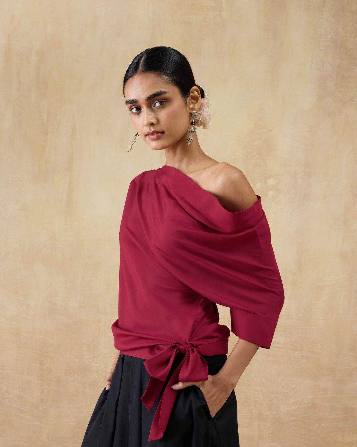 Person wearing a red one-shoulder Tokyo top with a side waist bow.